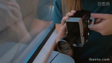 年轻的女乘客在火车上用复古<strong>摄像机</strong>拍摄外面的景色